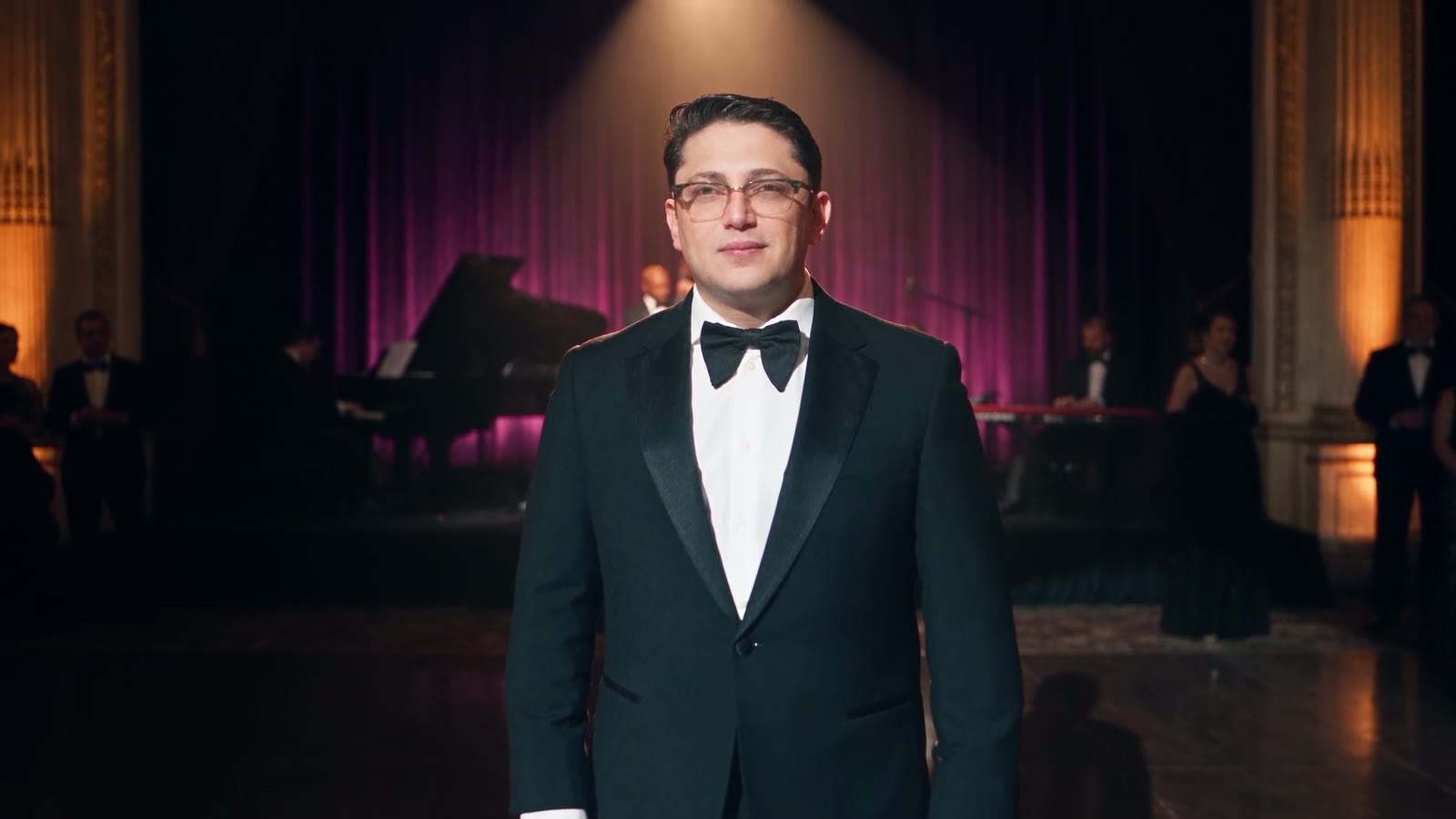 Lazar alone in the foreground beneath a warm spotlight